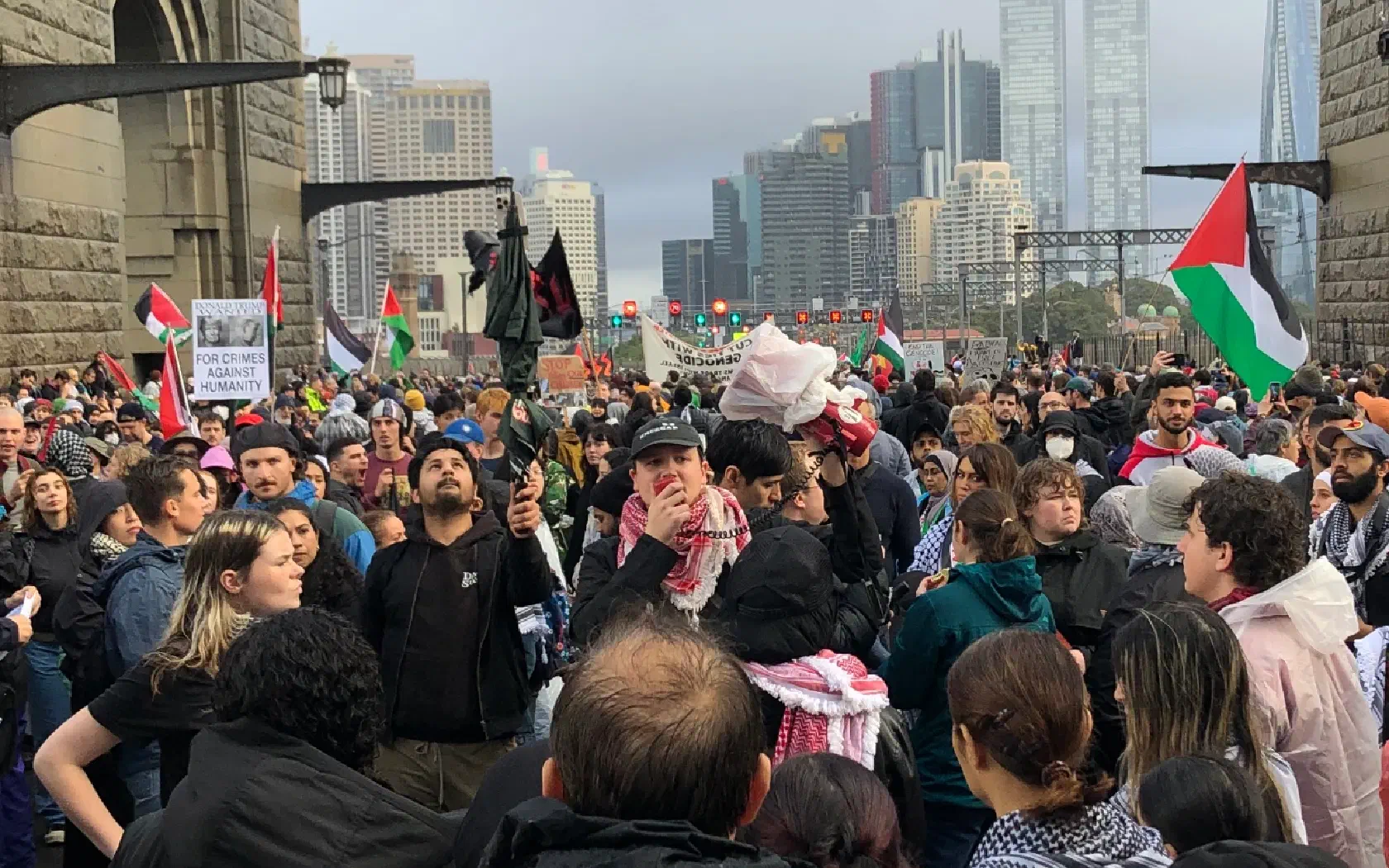 A crowd gathers around a man holding a megaphone on the Sydney Harbour Bridge march.
