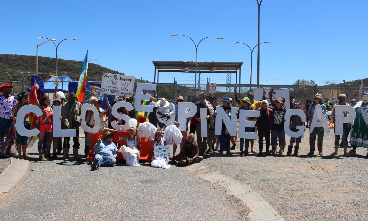 Protestors hold up large cutout letters to create the words 'Close Pine Gap' outside Pine Gap