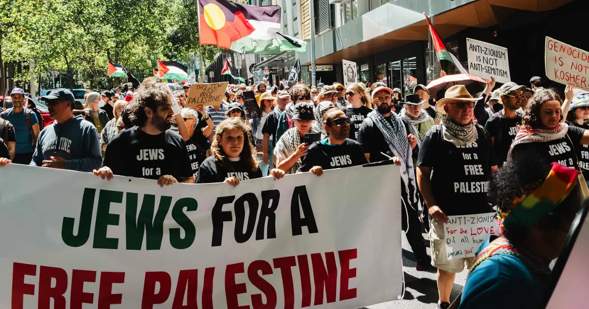 A crowd of protesters march down the street carrying pro-Palestine banners 
