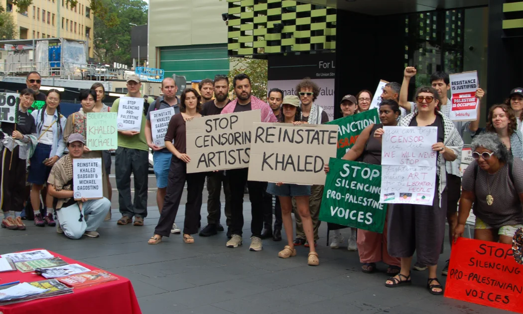 Protestors hold up signs calling on Creative Australian to reinstate artist Khaled Sabsabi