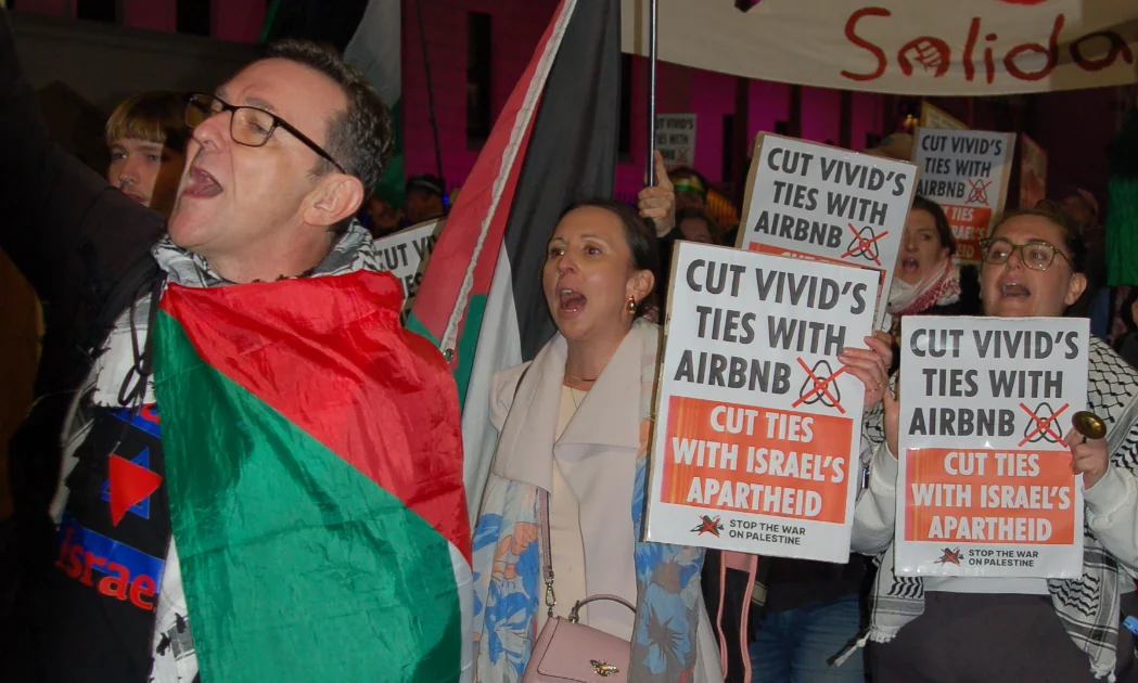 Protestors march through Sydney holding placards with the text: Cut Vivid's ties with Airbnb